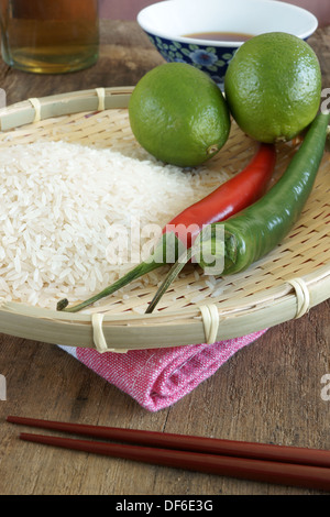 Limes, chilli's, rice and soy sauce, Asian food ingredients. Focus on Chilis and rice in foreground Stock Photo