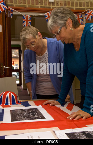 Elderly woman browsing old photographs at a village history open day ...