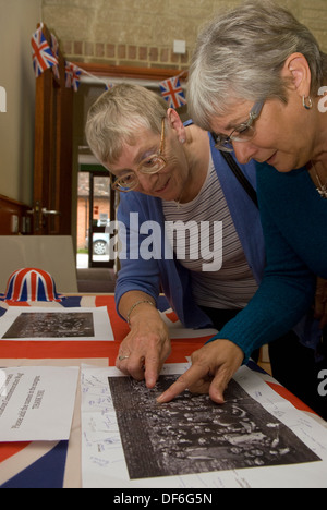 Elderly woman browsing old photographs at a village history open day ...