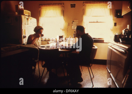 Mr. and Mrs. Wallace A. Wolf are shown having breakfast before he departs for his job as an automotive mechanic working for the city. The photo reflects daily life and working-class routines. Stock Photo
