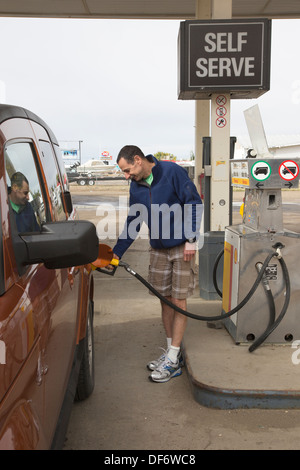 Man on road trip pumping gas into his truck at self service station in Alberta, Canada Stock Photo