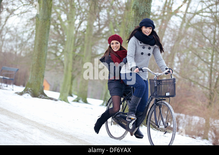 Two attractive women on a bike ride enjoying the cold outdoors Stock Photo