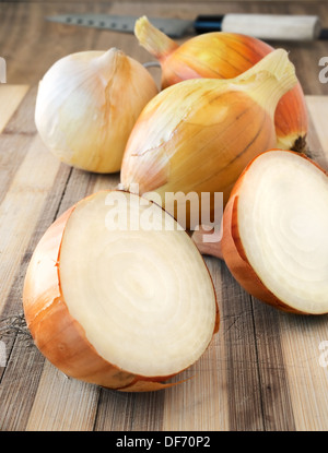 Fresh white onions on the wooden rustic kitchen cutting board. Stock Photo