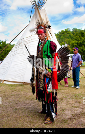 Native American Indian warrior with weapons standing in front of Tipi Tepee Stock Photo