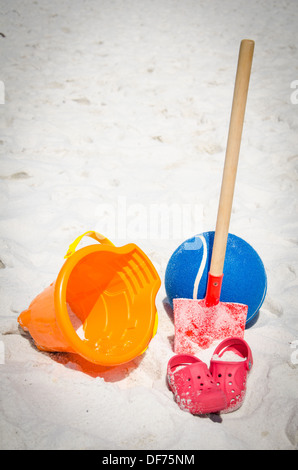 Bucket and Spade with blue ball and crocs on the beach Stock Photo