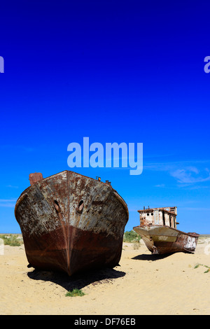 Rusty boats lay still on the dry desert sea bed of the dried Aral sea. Stock Photo