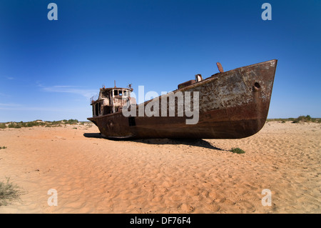 Rusty boats lay still on the dry desert sea bed of the dried Aral sea. Stock Photo