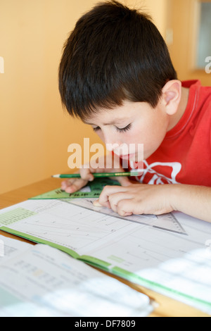 boy doing school homework from mathematics, geometry in workbook Stock Photo