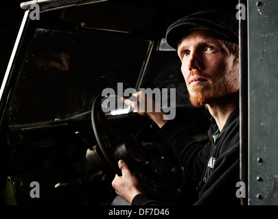 Man with a hat sitting in the driver's seat of an old car, looking up, Inneralpbach, Tyrol, Austria Stock Photo