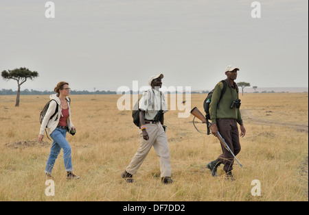 Tourist with armed guard and guide on a walking safari, Massai Mara, Serengeti, Rift Valley province, Kenya Stock Photo