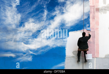 Painter paints bright blue sky on the urban wall Stock Photo