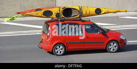 Car roof rack loaded with two kayak canoes driving along motorway Stock Photo