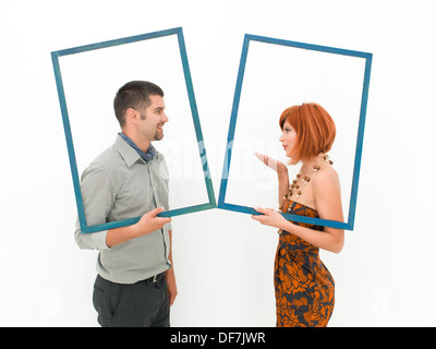 side view of man and woman holding two empty frames and kissing on white background Stock Photo
