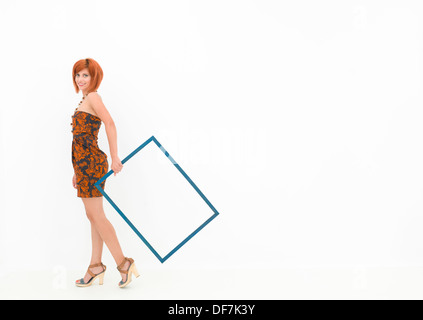 caucasian woman holding an empty wooden frame and walking on white background Stock Photo