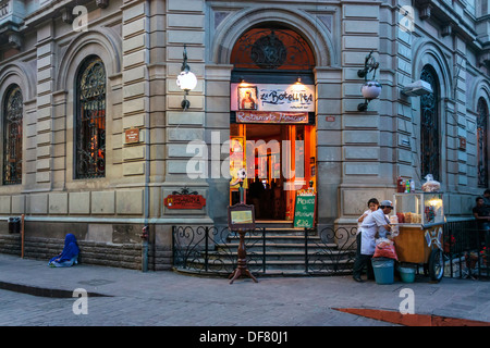 Picturesque shop, street food vendor and beggar woman on street corner in 16th century historic district of Guanajuato, Mexico. Stock Photo