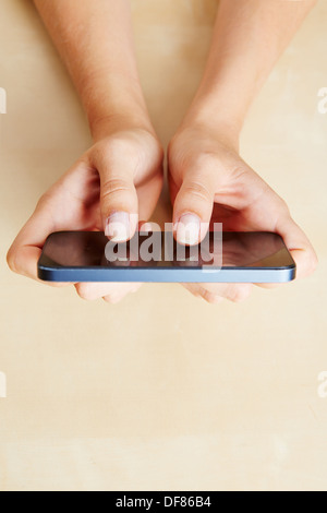Two female hands holding a smartphone on table Stock Photo