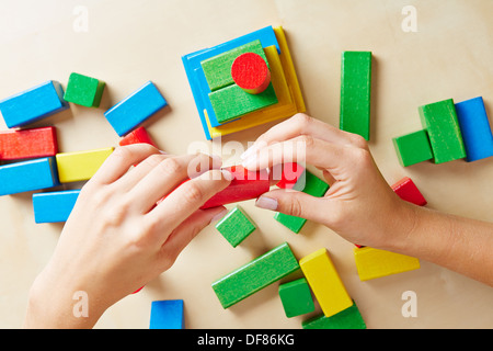 Two hands building a tower with colorful wooden building blocks Stock Photo