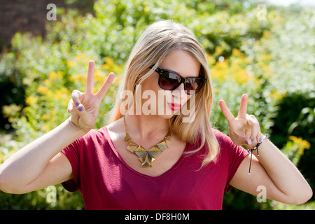 Beautiful teenage girl; Attractive blond british caucasian teenage girl age 18-19 years, head and shoulders portrait posing with sunglasses,  UK Stock Photo