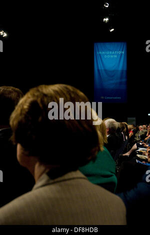 Manchester, UK. 30th Sep, 2013. A delegate sits in the conference hall of the Conservative Party Conference 2013 whiere a banner proclaims the fall of immigration under the current government Credit:  Paul Swinney/Alamy Live News Stock Photo