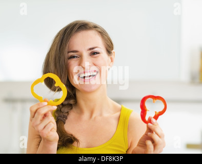 Smiling young woman holding two slices of red and yellow bell pepper Stock Photo