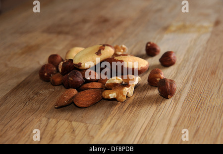 Mixed nuts on chopping board including hazelnuts walnuts brazil and almonds Stock Photo