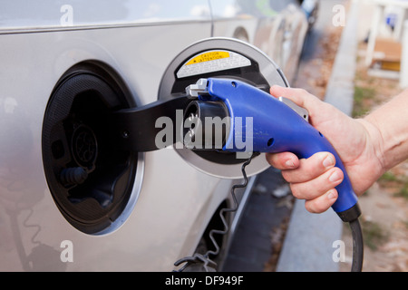 Man inserting charger on electric car Stock Photo