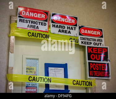 Safety reminders, no trespassing and danger signs bar entry during an asbestos remediation project in New York Stock Photo