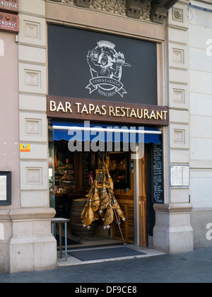 BARCELONA, SPAIN - SEPTEMBER 12, 2013: Hams hanging in entrance to Tapas Bar Restaurant in the Eixample Quarter Stock Photo