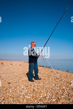 Beach Angler Fishing On A Shingle Beach UK Stock Photo