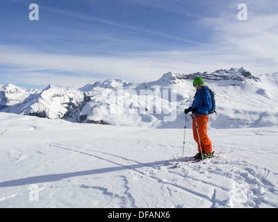 Male skier skiing in Le Grand Massif ski area looking at snowcapped mountains in the French Alps. Flaine, Rhone-Alpes, France Stock Photo