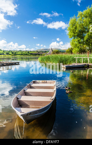 Rowing boats moored at Llangors Lake in the Brecon Beacons National Park, Wales with the crannog beyond. Stock Photo