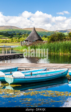 Rowing boats moored at Llangors Lake in the Brecon Beacons National Park, Wales with the crannog beyond. Stock Photo