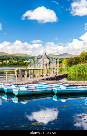 Rowing boats moored at Llangors Lake in the Brecon Beacons National Park, Wales with the crannog beyond. Stock Photo