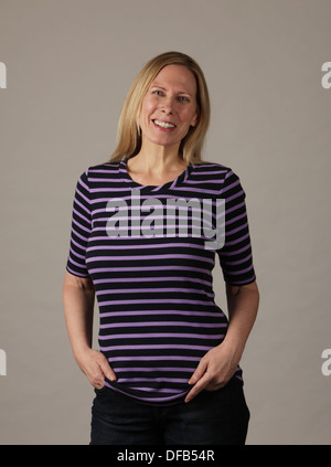 Smiling attractive middle aged woman with hands in pockets looking at camera, USA Stock Photo