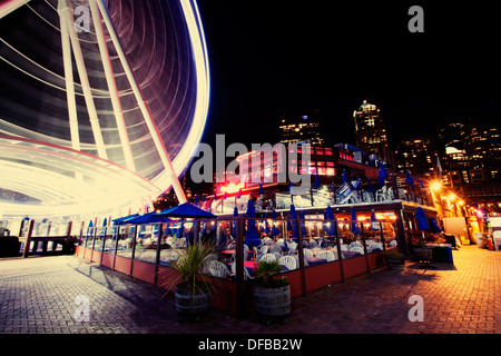 Great Wheel of Seattle at night as seen from the pier with Fisherman's Restaurant in the foreground Stock Photo