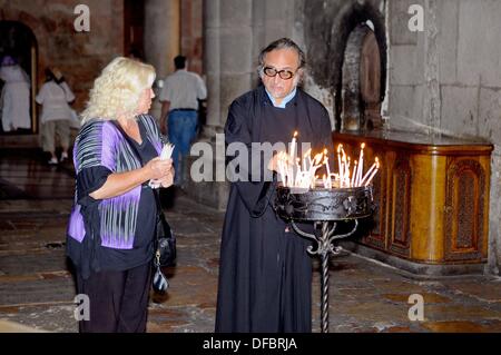 A believer talks to a priest before visiting the most important site of the Church of the Holy Sepulchre, the Aedicule (Holy Grave, Grave Chapel), the supposed location of Jesus' grave and the 14th station of the Via Dolorosa, that is visited by thousands of pilgrims and tourists daily, in Jerusalem, Israel, 10 September 2013. The Via Dolorosa (Way of Suffering) is a street in the old town of Jerusalem named after the path Jesus of Nazareth walked to his crucification. Jesus carried the cross, on which he later died via that road from the Antonia Fortress, then seat of Pilate, to Golgotha, the Stock Photo