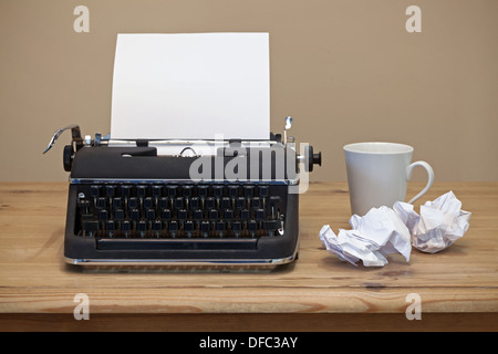 An old retro typewriter on a desk  with a piece of blank paper for you to add your own copy if required. Stock Photo