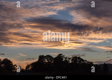 EVENING SKY WITH DRAMATIC CLOUDS UK . Trees silhouetted against sky. Stock Photo