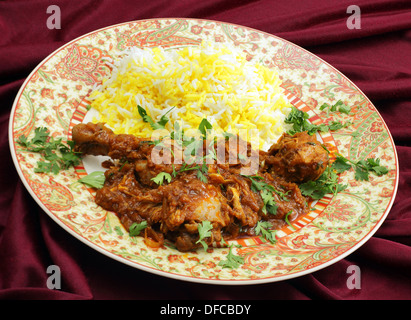 Homemade butter chicken masala with yellow and white rice, garnished with chopped coriander leaves. Stock Photo