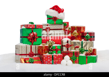 A stack of gift wrapped Christmas presents on snow, isolated against a white background. Stock Photo
