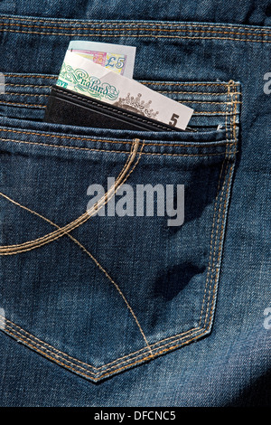Close up of leather wallet showing English cash banknote banknotes money in the back pocket of denim jeans leading to pickpocketing England UK Stock Photo