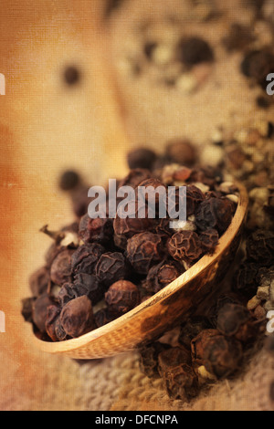 black peppercorns served in a spoon, rustic background texture applied. Background texture image also my own work. Stock Photo