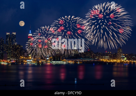 The full moon rising over the New York City skyline as the Macy's Spectacular 4th of July Fireworks Celebration Show begins. Stock Photo