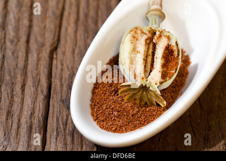 Sliced poppy capsule is in a bowl with poppy seeds on a rustic wooden table Stock Photo