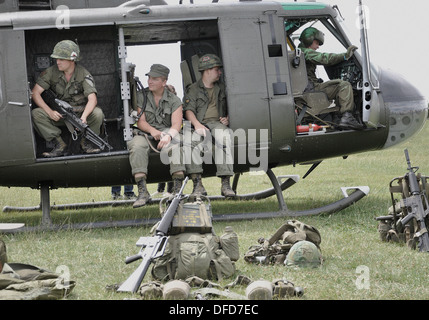 Bell UH-1 'Huey' US Army helicopter with re-enactors to represent Vietnam War scenario. Image 'aged' digitally to seventies era faded colour. Stock Photo