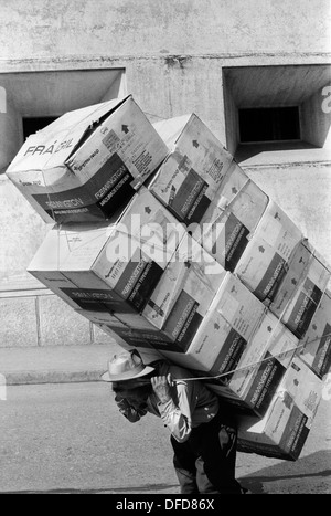 Guatemala City Central America. 1973. Back breaking work man carrying Remington Standard Typewriter boxes.  1970s HOMER SYKES Stock Photo