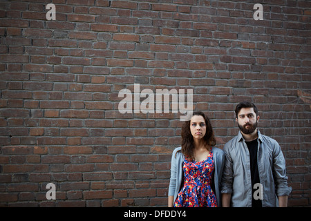 Portrait of serious couple standing by the brick wall Stock Photo