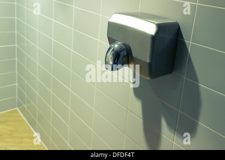 Silver hand dryer on a grey tiled wall Stock Photo