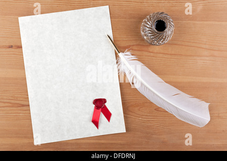 A blank piece of parchment paper with red wax seal, plus feather quill and glass ink well on a desk Stock Photo