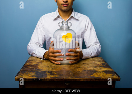 Transparent piggy bank sitting on table, young man in background ...